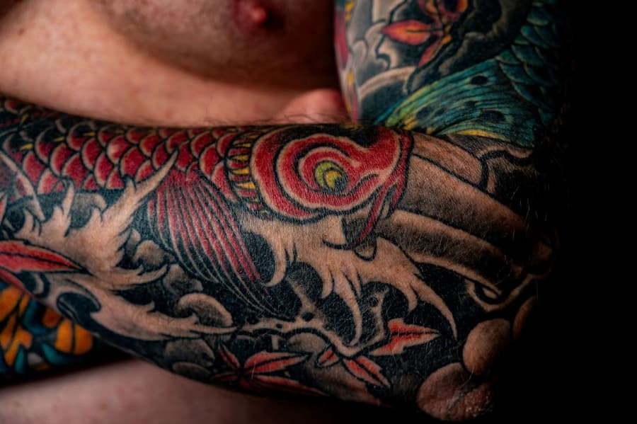 Healed red koi and maple leaves in colour across a forearm
