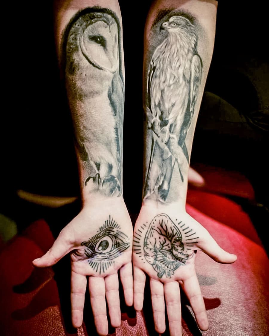 Healed owl and hawk on paired forearms, an eye on each palm