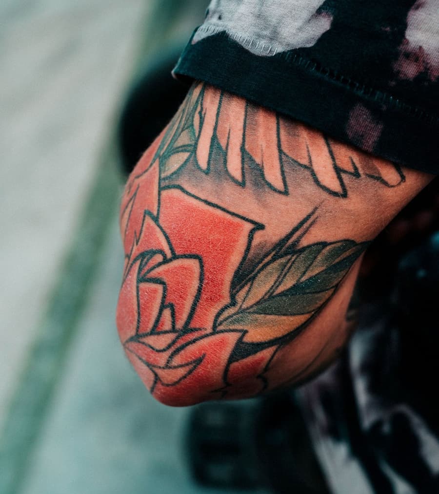 Healed bold red rose and leaves wrapping an elbow