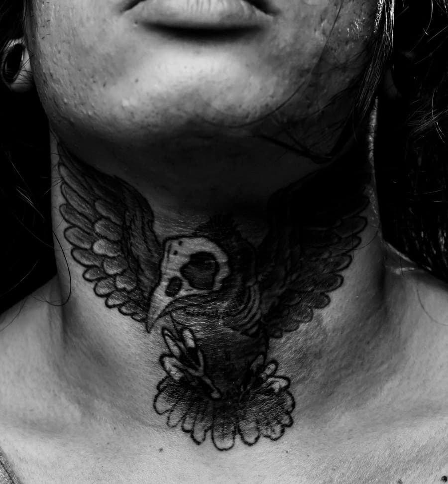 Healed black hawk with spread wings over a skull on a throat