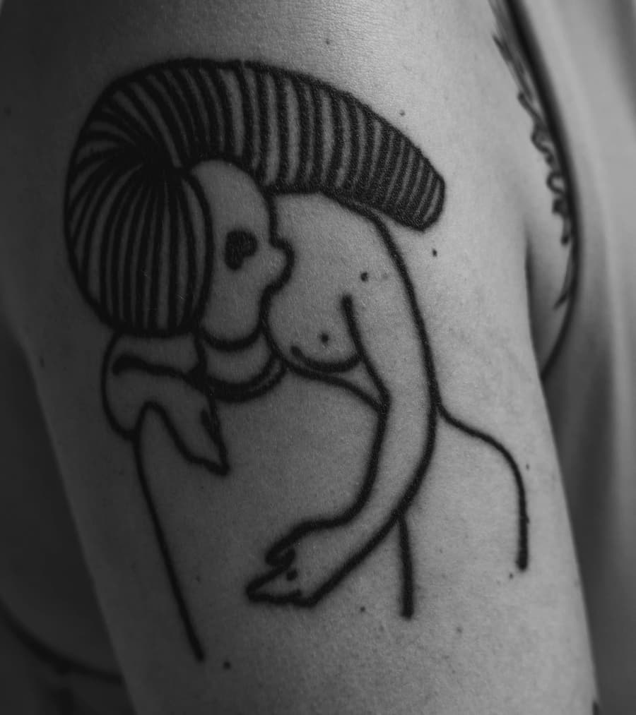 Healed bold line figure tattoo on an upper arm, in black