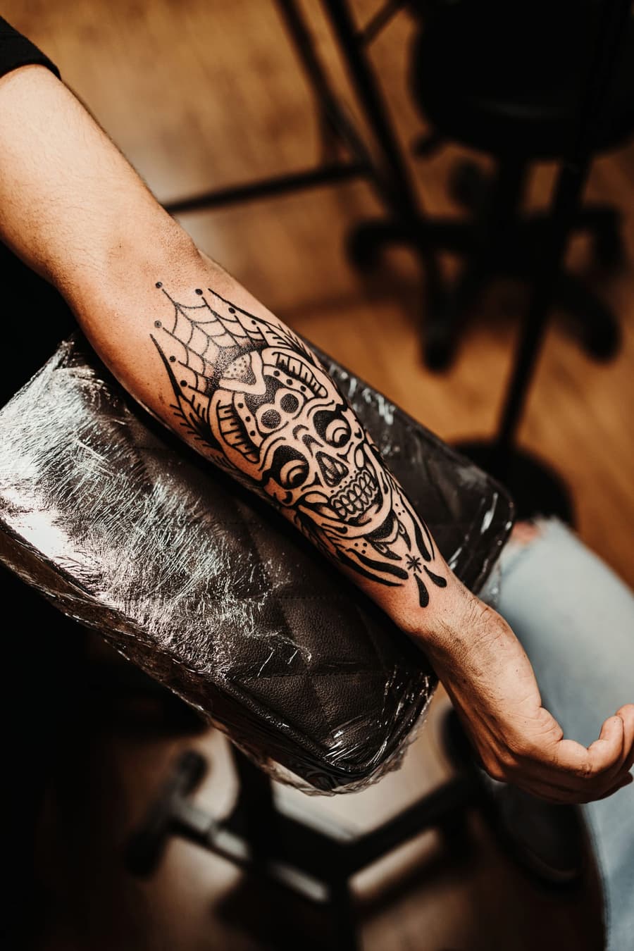 Fresh blackwork skull framed by a spider web on a forearm