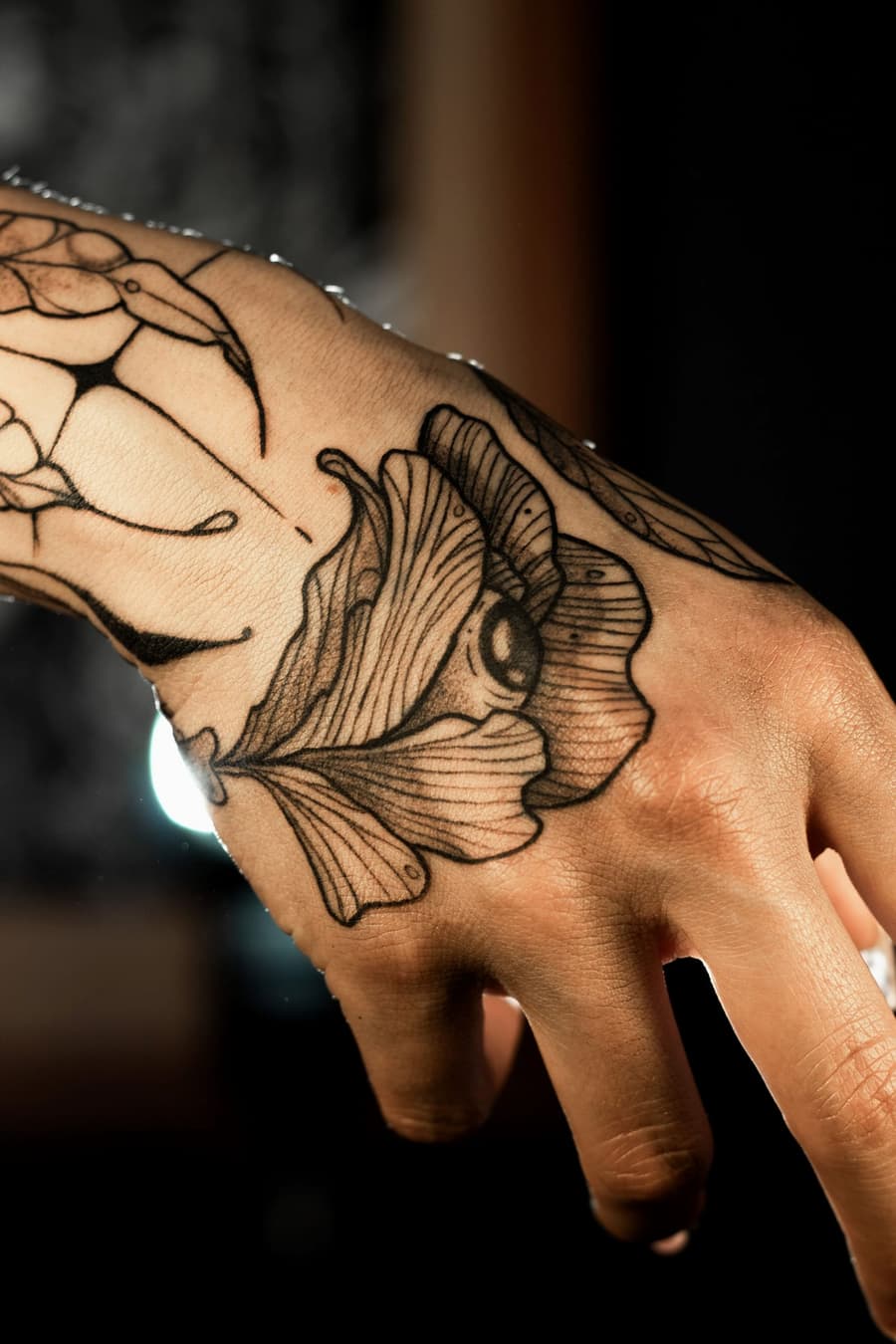 Healed fine line ginkgo leaf and moth across the back of a hand