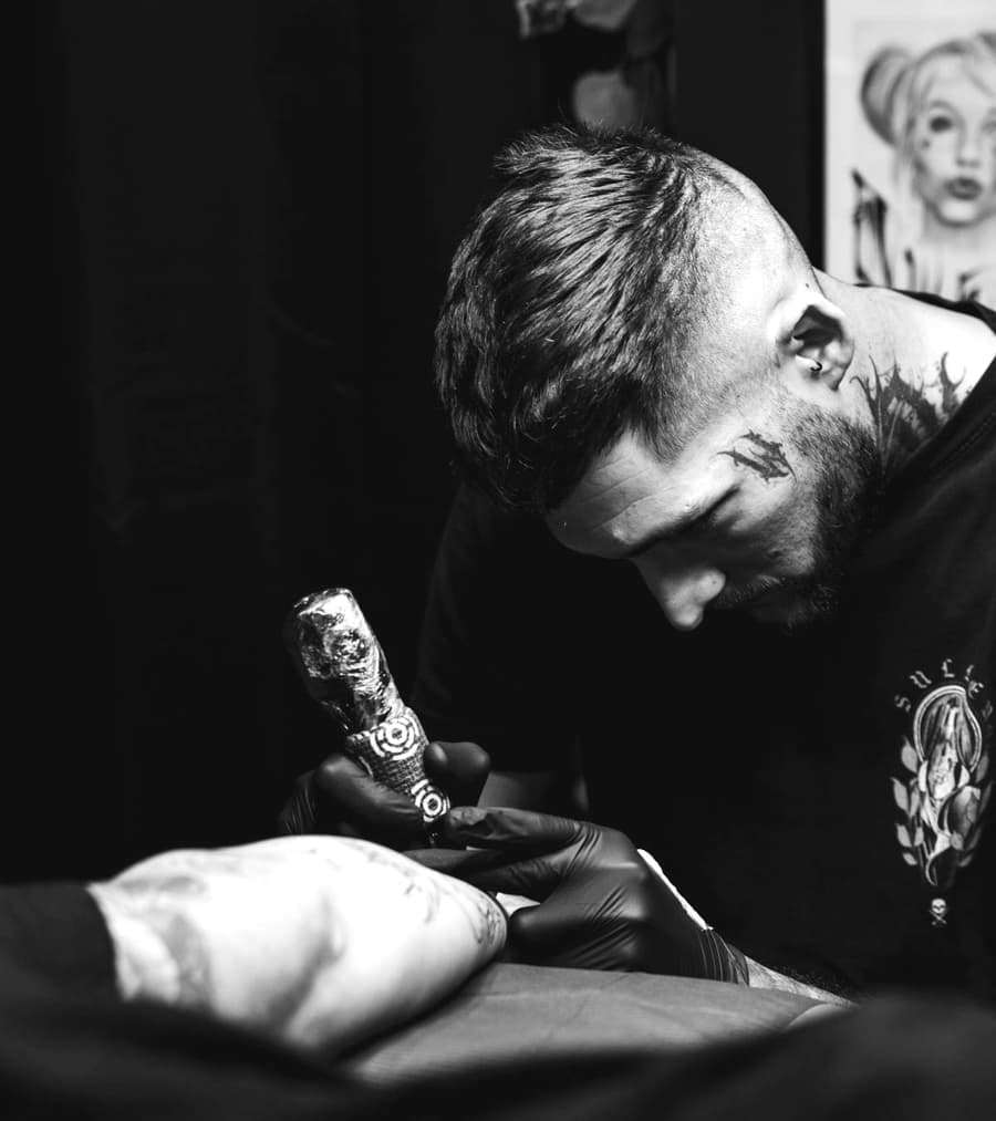 Jonah Reyes leaning in over a client with a tattoo machine