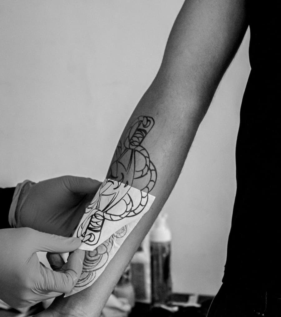 A stencil being peeled from a forearm, the purple transfer left behind