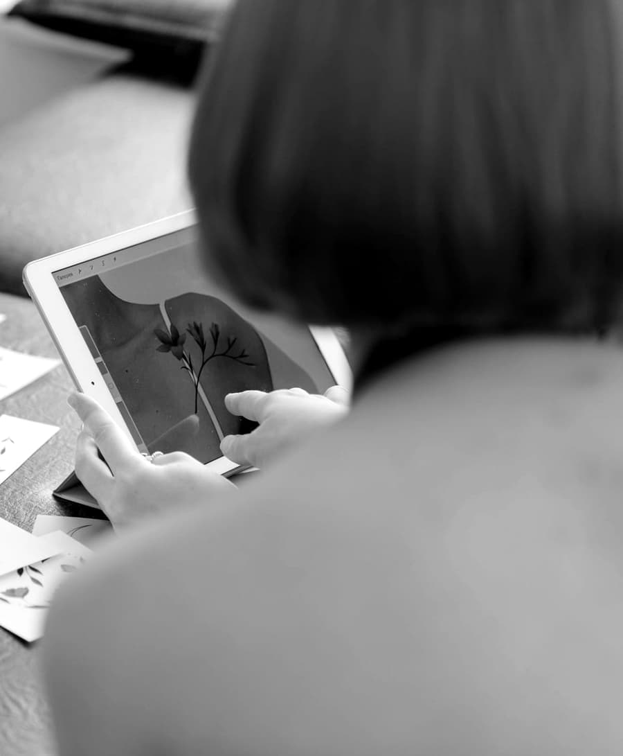 Tess Albright drawing floral designs on a tablet, flash cards spread on the desk