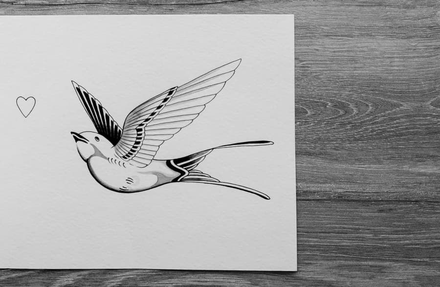 Flash drawing of a traditional swallow in flight beside a small heart