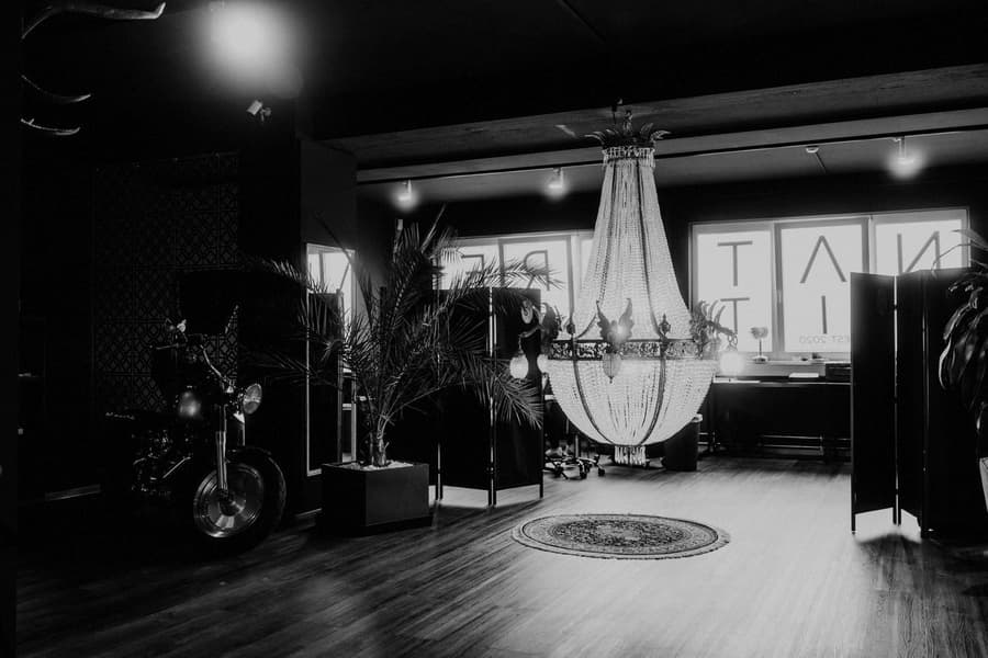 The long room: a chandelier over a timber floor, chairs along the wall, in black and white