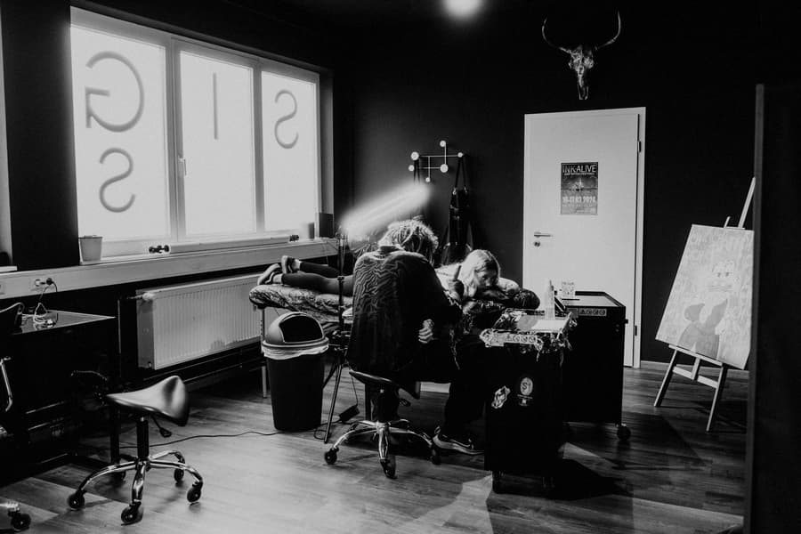Inside the studio: an artist at work under a lamp, stag skull on the wall, in black and white