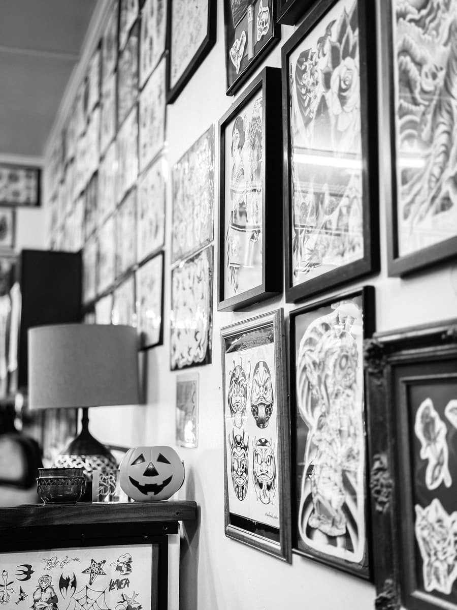 A studio wall covered in framed flash and artwork, in black and white